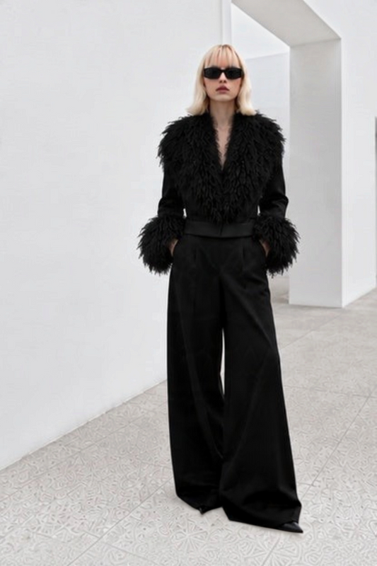 Model wearing Svart Studio black cropped jacket with Mongolian sheep wool collar and cuffs and matching wide trousers.